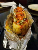 美味寿司包裹在铝箔中,顶部配有鱼子酱和葱,餐厅食物。