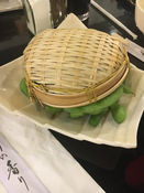 竹制蒸笼里的毛豆,放在一个盘子里,准备食用美味的食物。