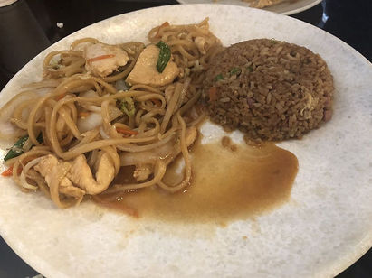 盘子上的炒面和米饭,配有鸡肉和酱汁,美味佳肴。